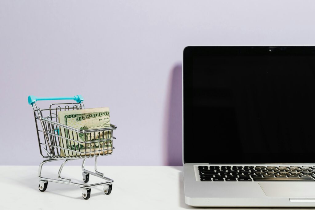 pexels-photo-5632397-5632397 Shopping cart with money next to a laptop symbolizing online shopping and e-commerce.